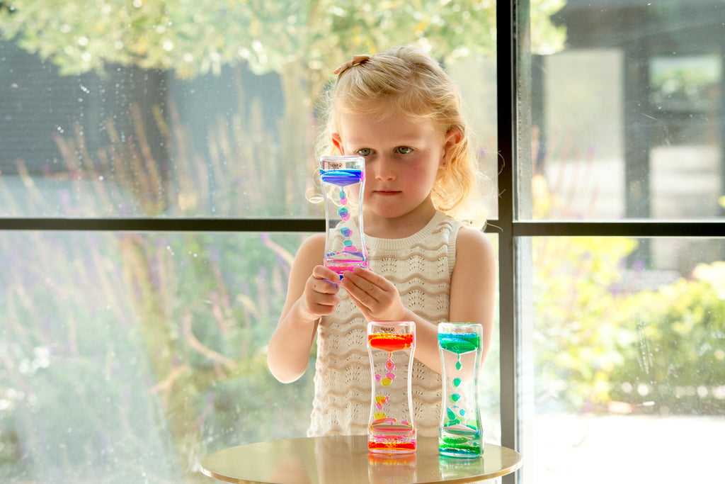 Rainbow sand timer held by child, with colorful beads in a clear hourglass tube