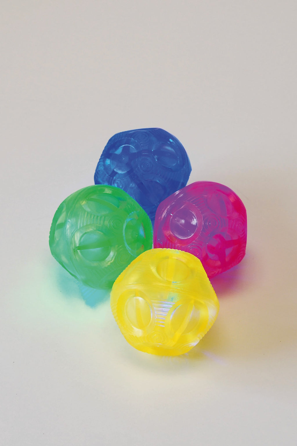 Four translucent flashing bounce balls, blue, green, pink, and yellow