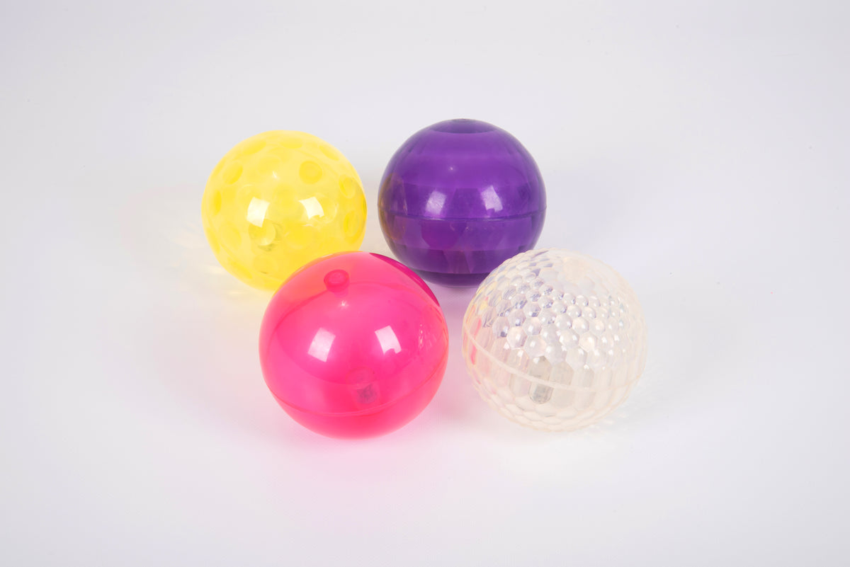 Four glossy textured sensory balls: yellow, purple, pink, and white with dot pattern