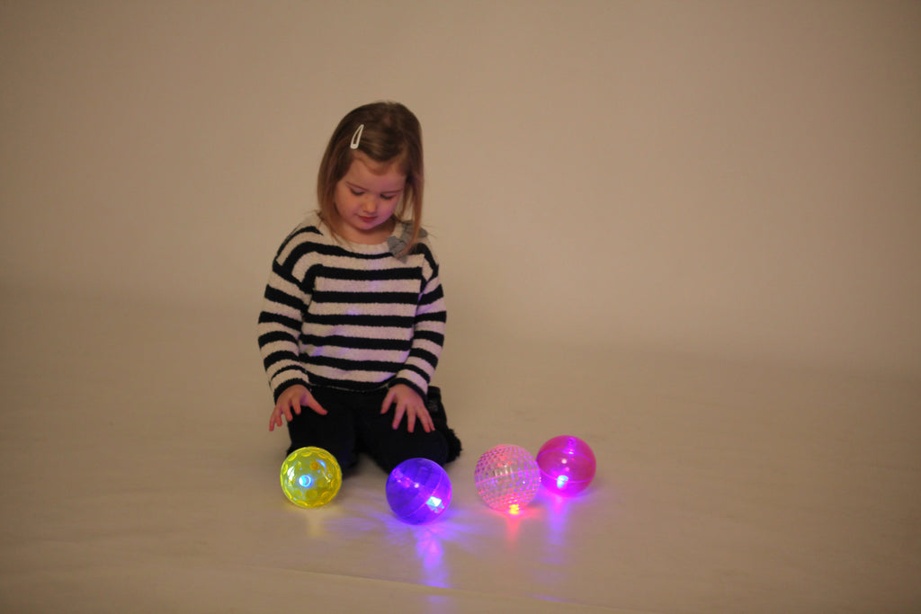 Three flashing sensory balls—yellow, purple, and pink—glowing with textured surface