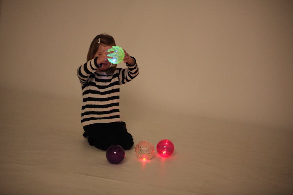 Flashing sensory balls—green, purple, and red/pink—glowing from textured shells