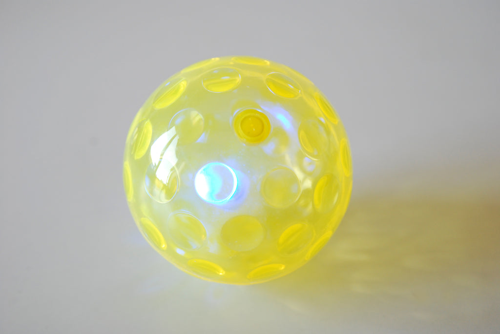 Yellow textured flashing sensory ball with glowing light through translucent shell