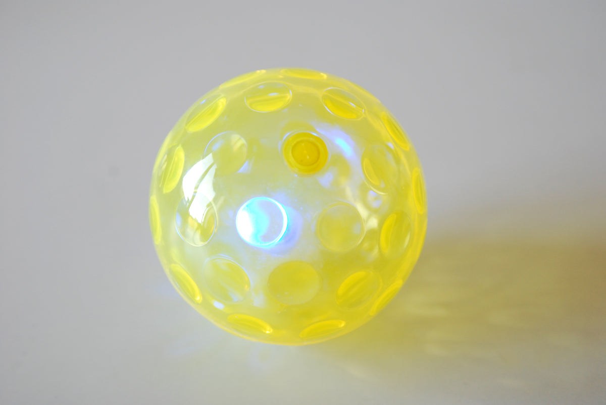 Yellow textured flashing sensory ball with glowing light through translucent shell
