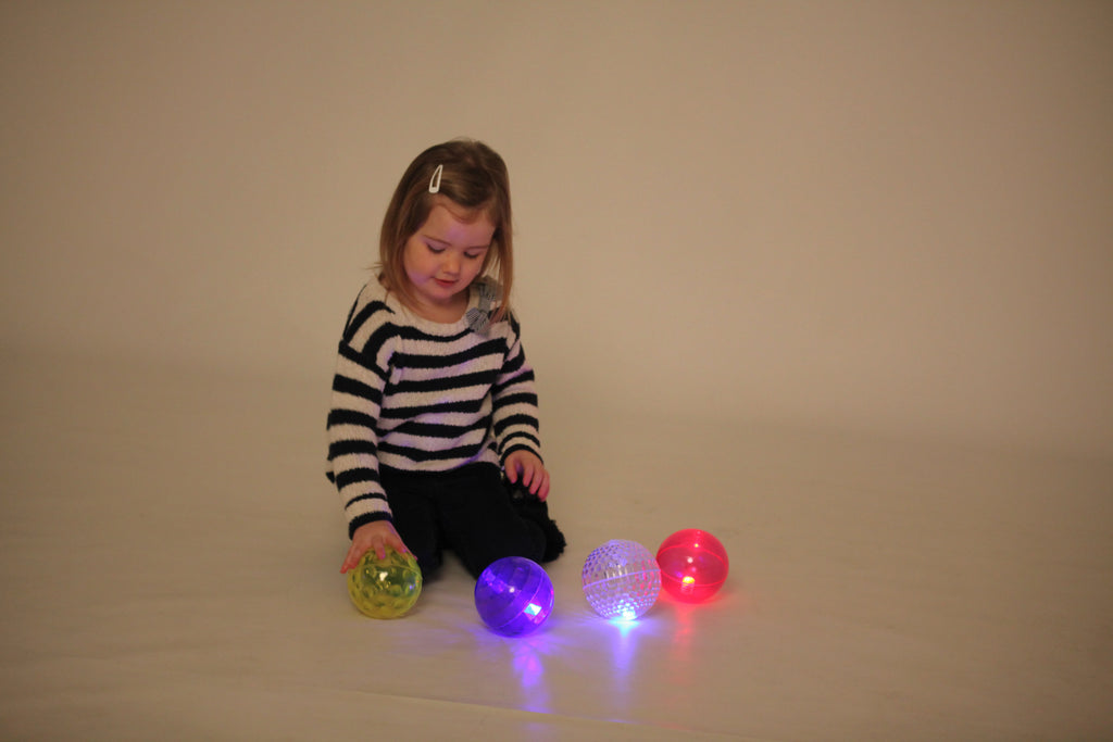 Flashing sensory balls in yellow, purple, and pink/red, glowing from textured shells