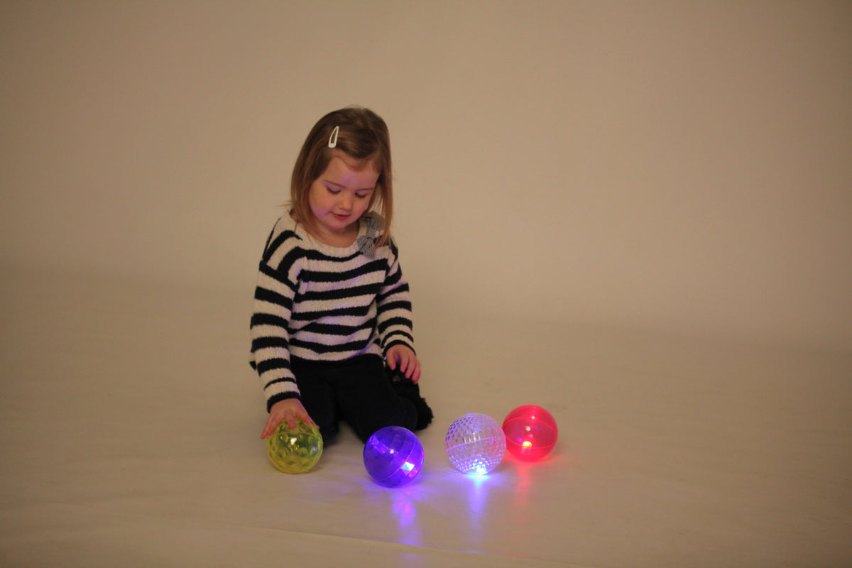 Flashing sensory balls in yellow, purple, and pink/red, glowing from textured shells