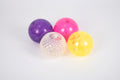 Set of four textured flashing balls in purple, pink, clear, and yellow