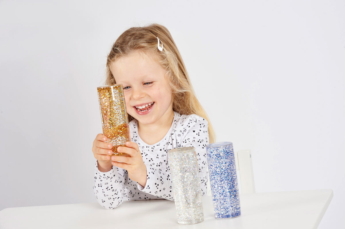 Glitter sensory tubes set, child holding blue, silver, and gold glitter cylinders