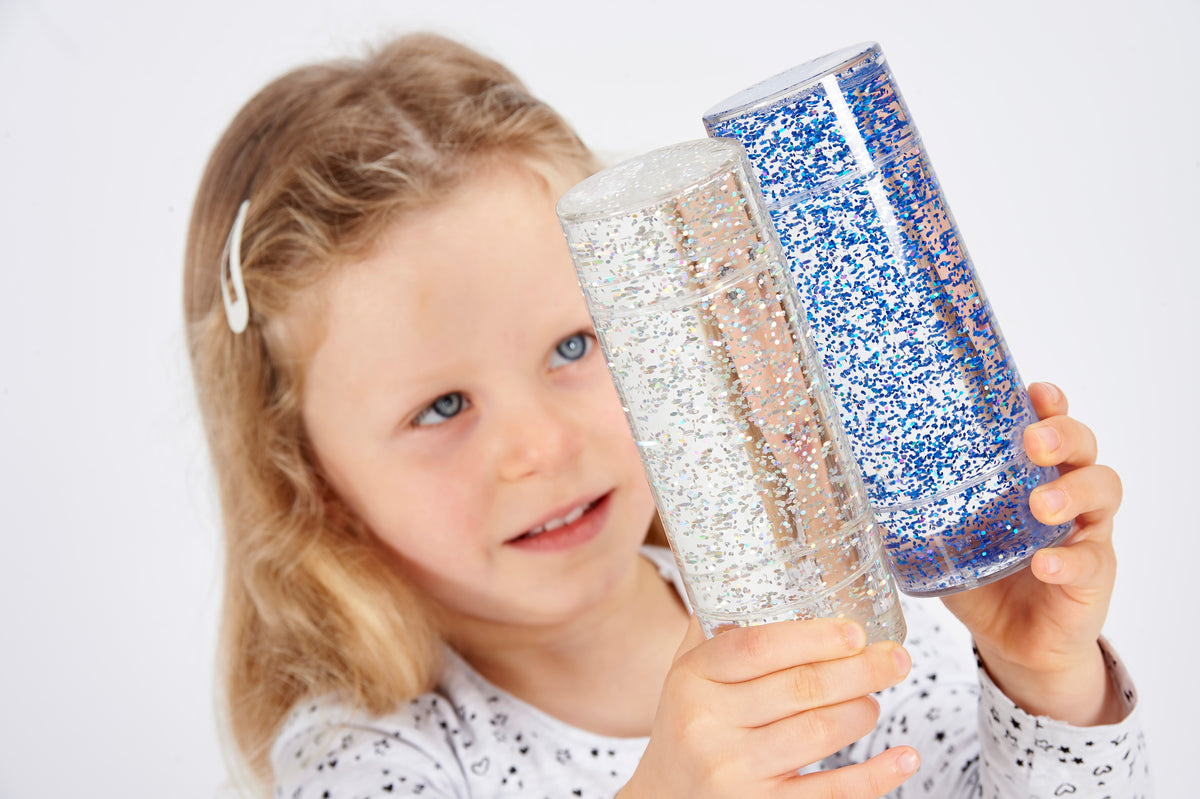 Glitter sensory tubes set, close-up of blue and silver glitter cylinders in hands