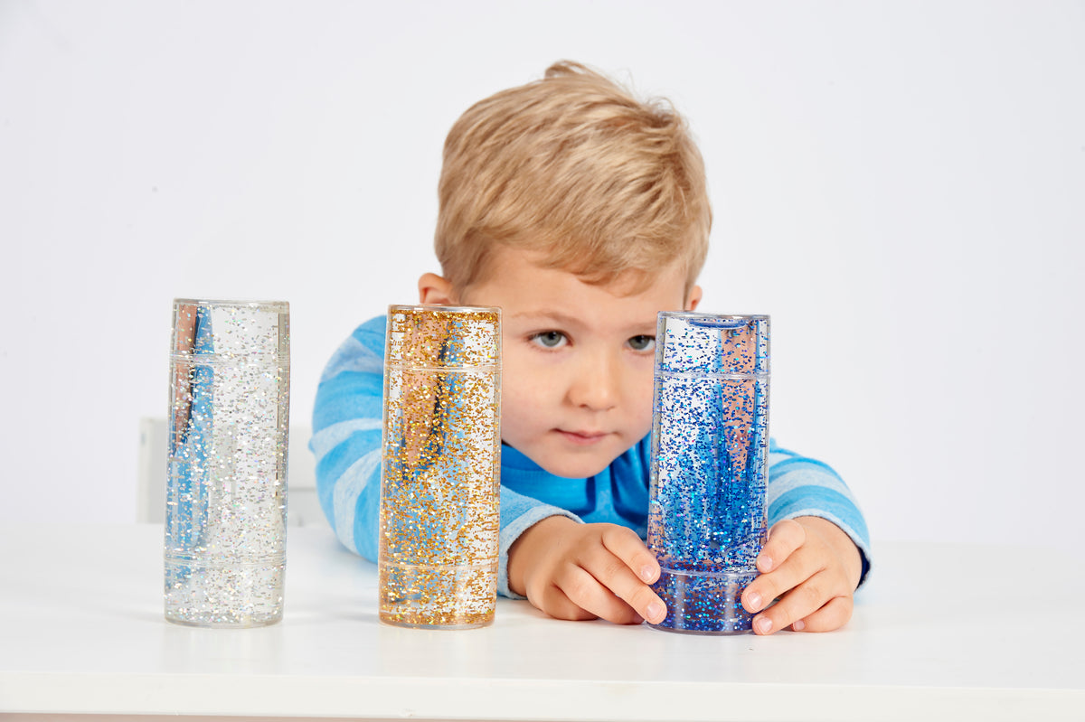 Glitter sensory tubes set, child holding blue and gold glitter cylinders in front