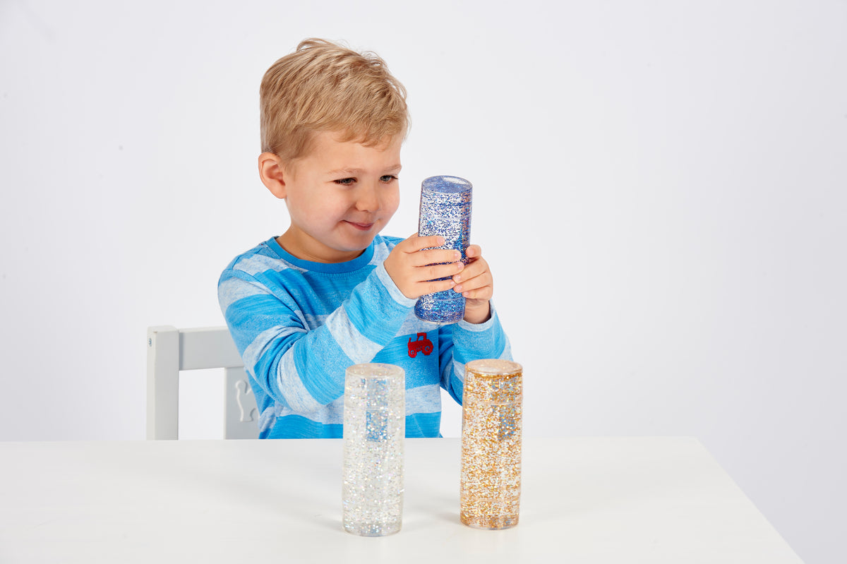 Glitter sensory tubes set, child holding blue, silver, and gold glitter cylinders