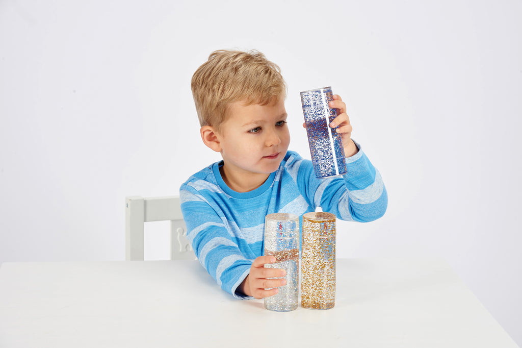 Glitter sensory tubes set, child holding blue, silver, and gold glitter cylinders
