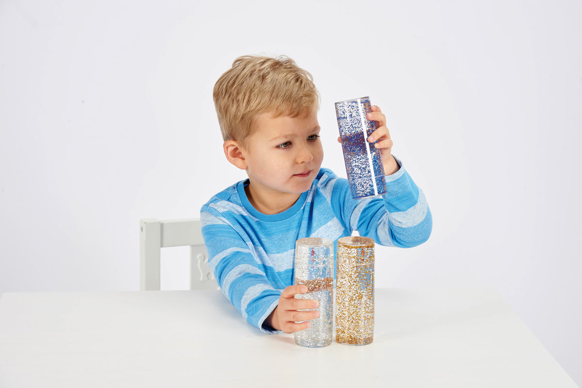 Glitter sensory tubes set, child holding blue, silver, and gold glitter cylinders