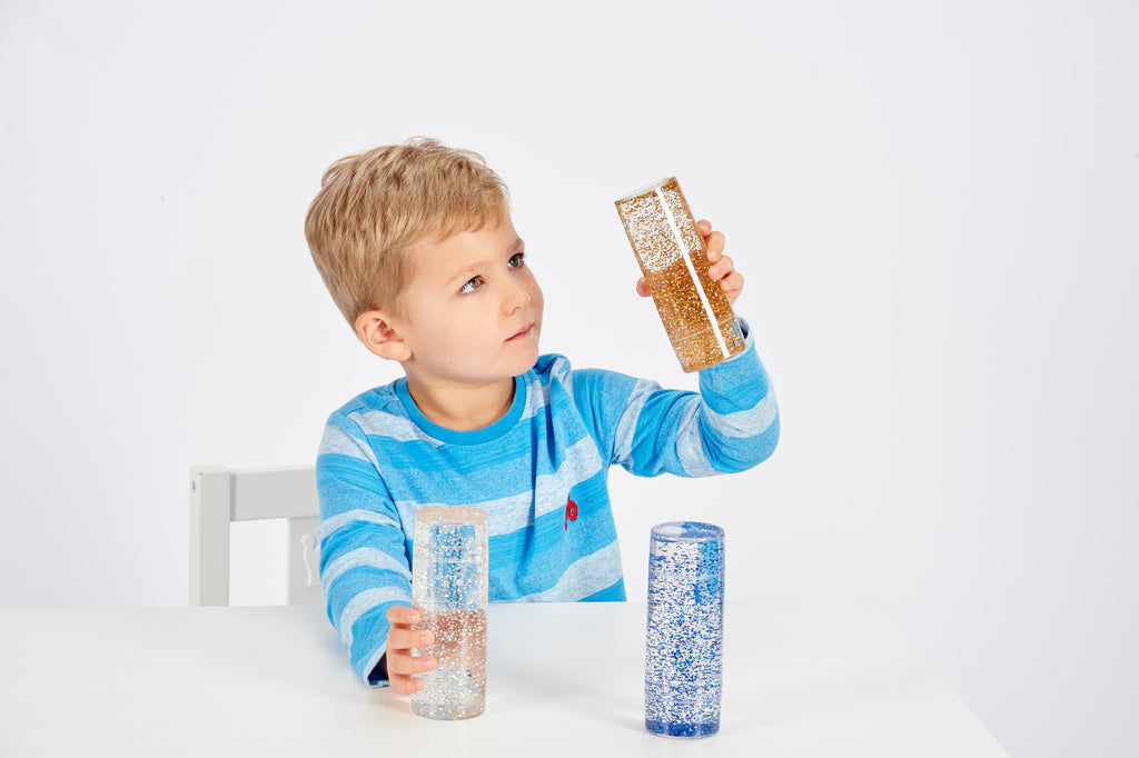 Glitter sensory tubes set, child holding blue, silver, and gold glitter cylinders