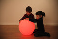 Red LED glow ball with two children playing