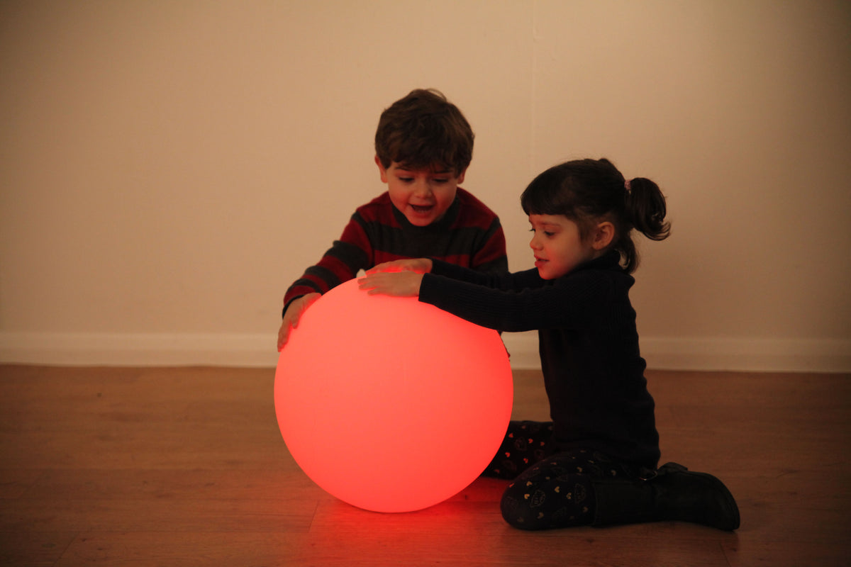 Red LED glow ball with two children playing