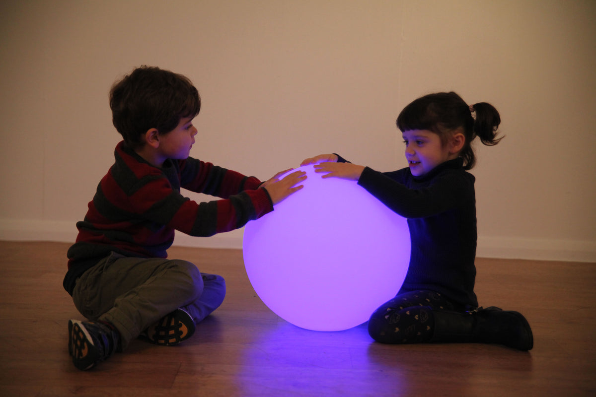Purple LED glow ball held by two children