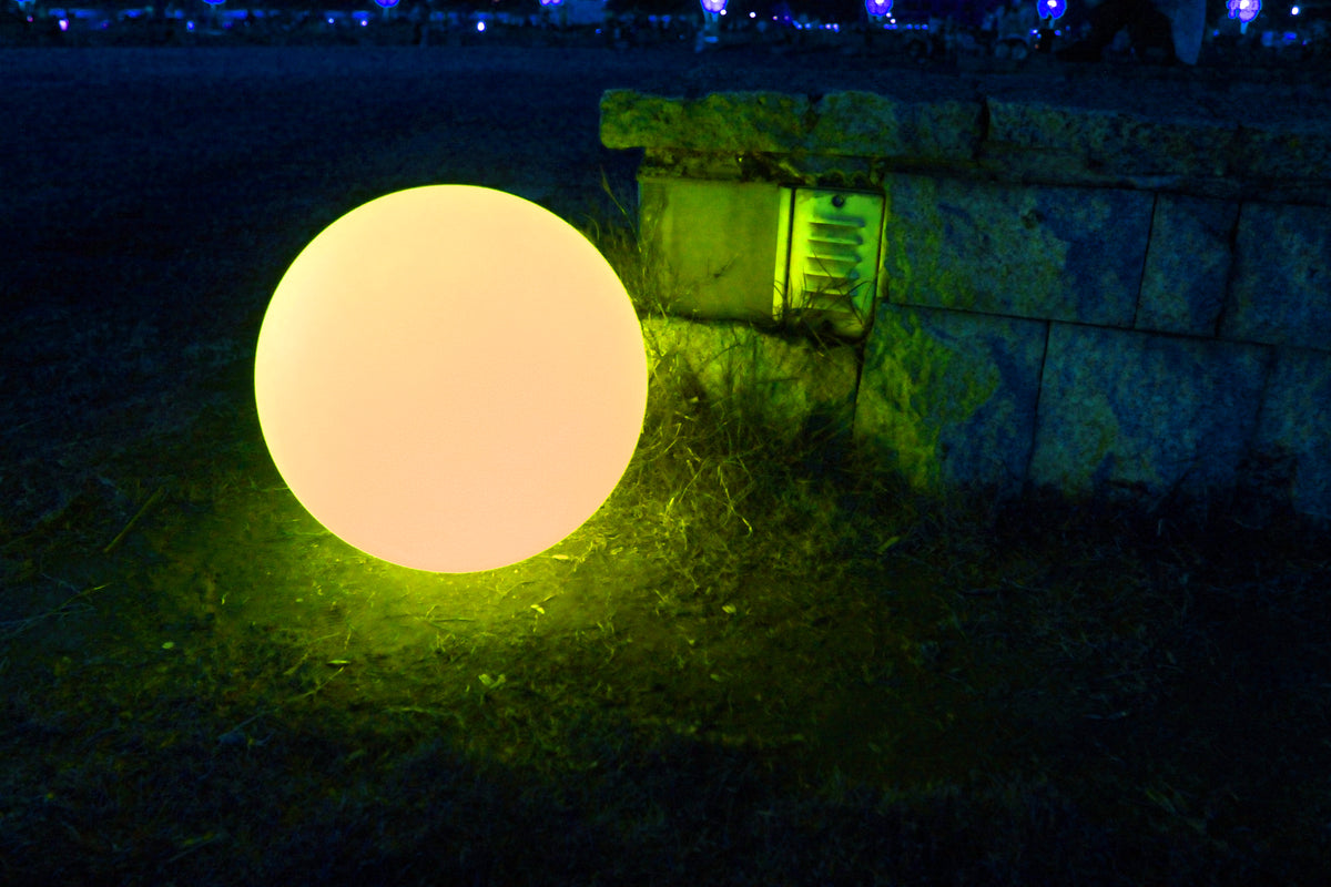 Outdoor green glow ball on grass near a stone wall