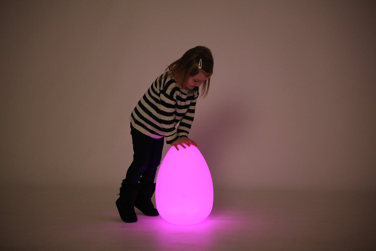 Glowing egg-shaped light with a child leaning toward the pink glow