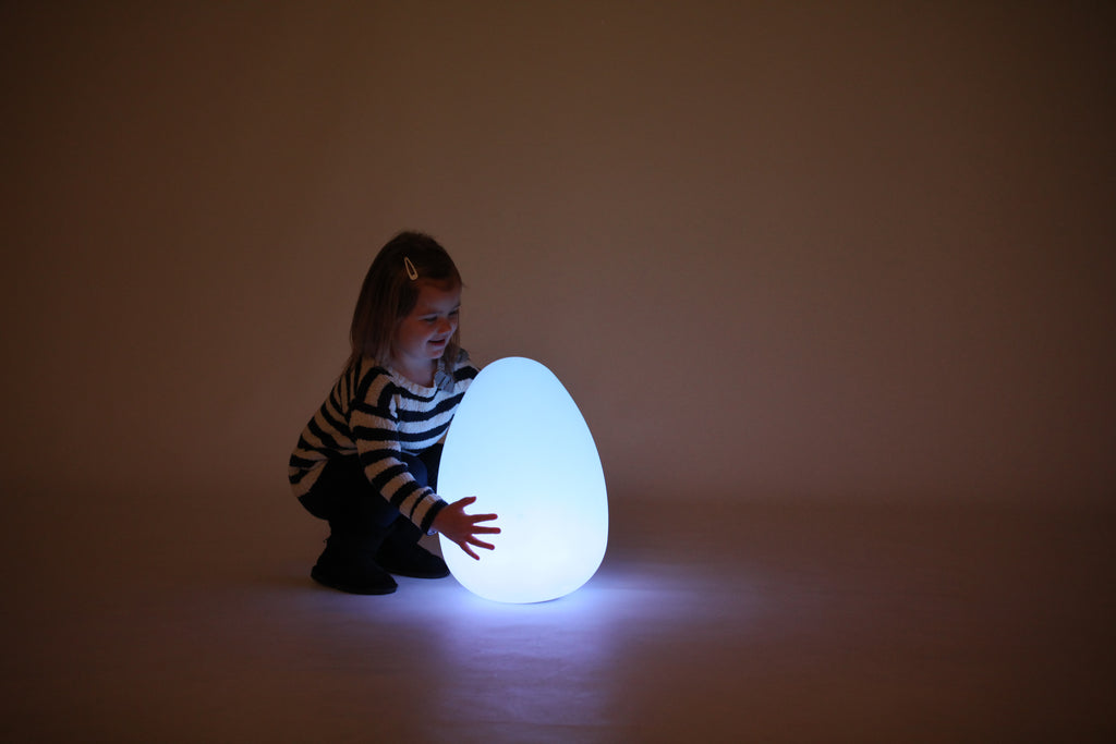 Glowing egg-shaped light with a child kneeling beside it