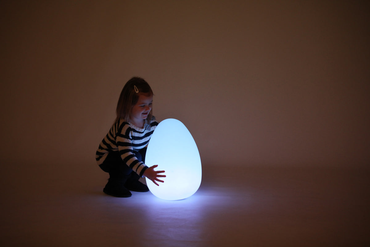 Glowing egg-shaped light with a child kneeling beside it