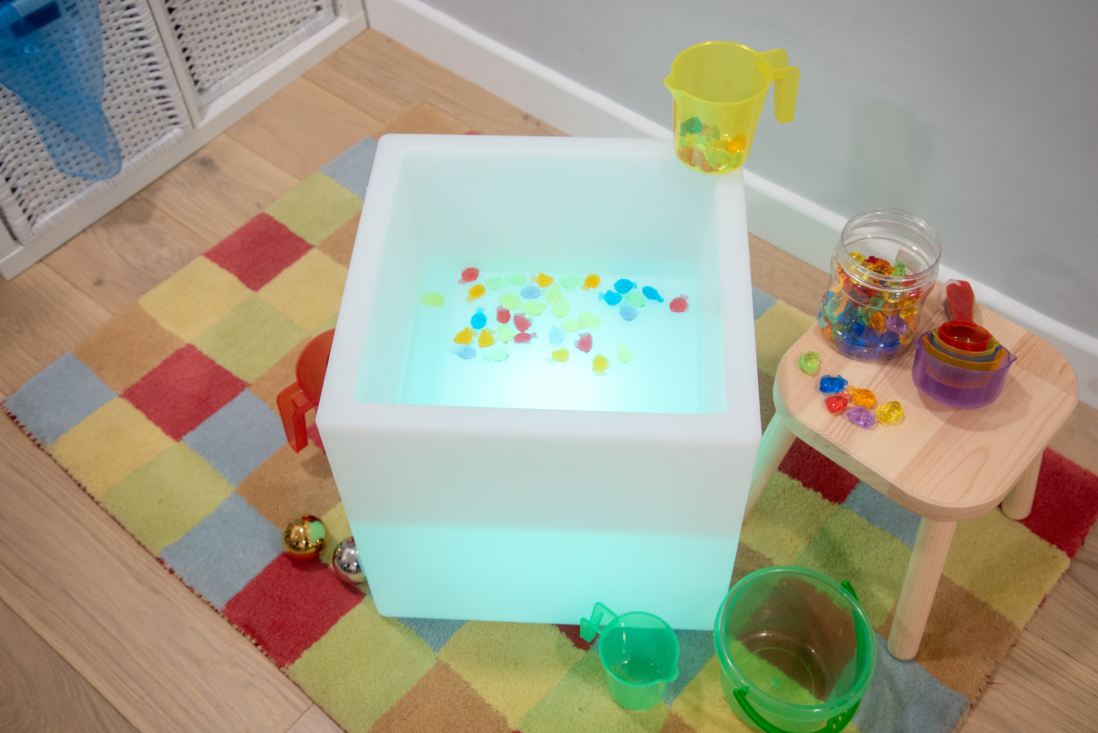 Sensory play cube with glowing basin and colorful translucent cups inside