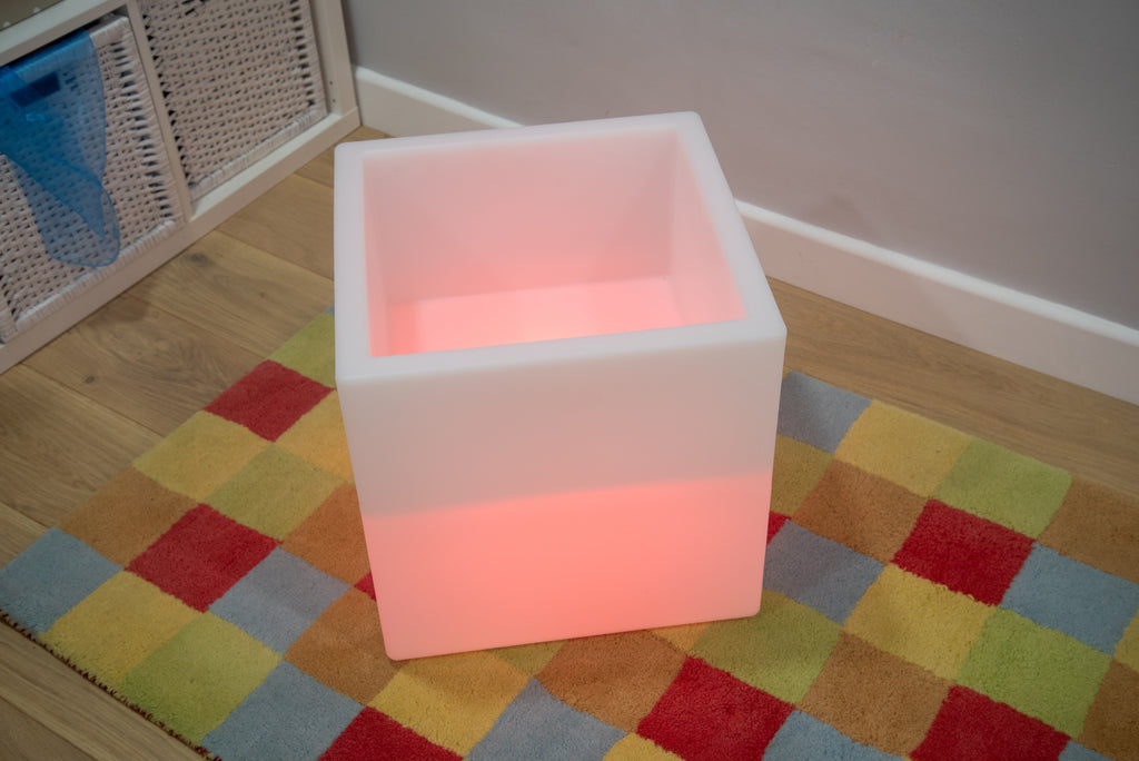 Glowing sensory play cube with soft pink light, front angle view