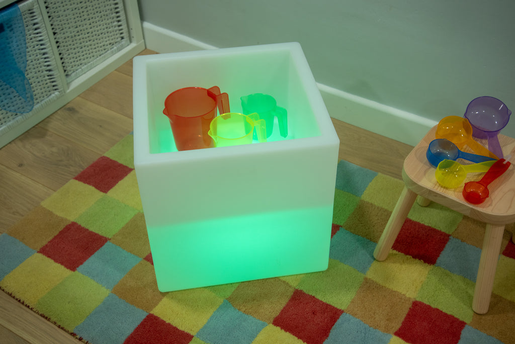 Sensory glow play cube with bright green light and colorful cups inside