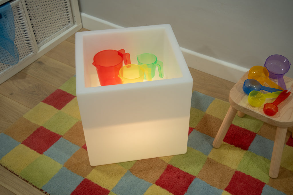 Sensory glow play cube with colorful translucent cups and scoop inside