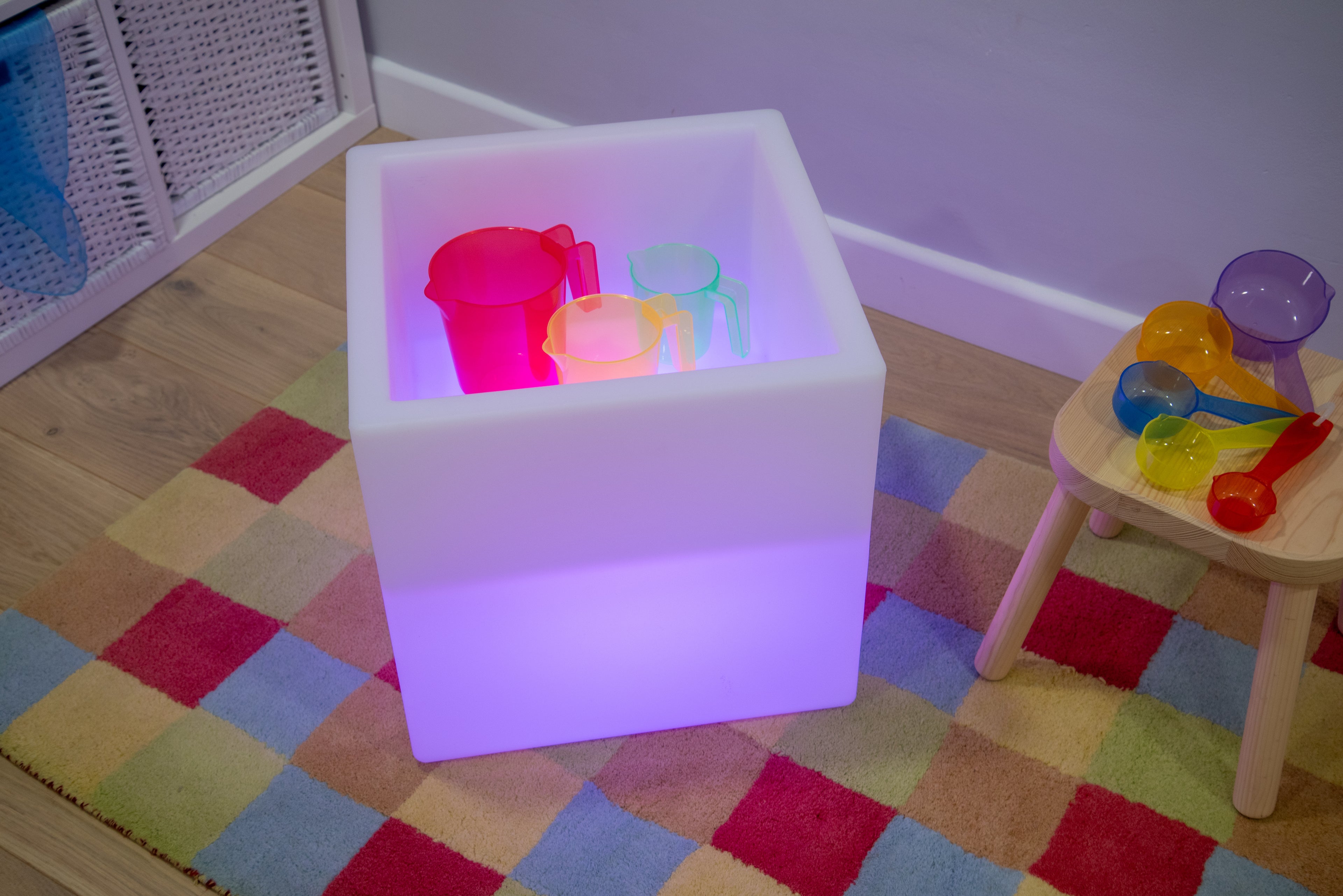 Sensory glow play cube with purple light and colorful translucent cups inside