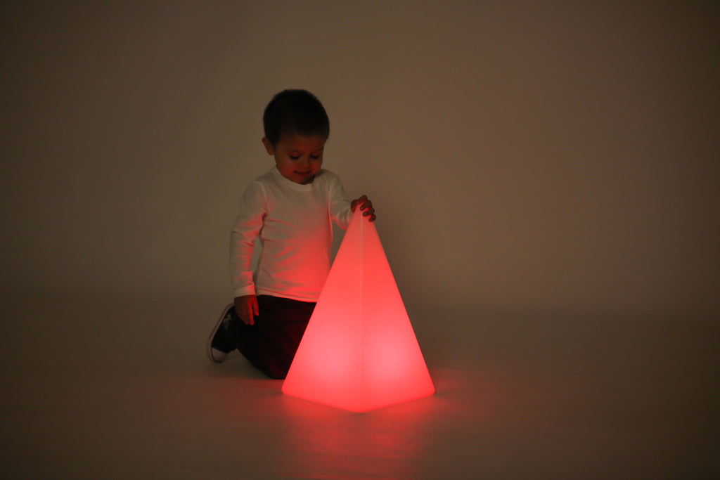Child interacting with glowing light pyramid, red light glow