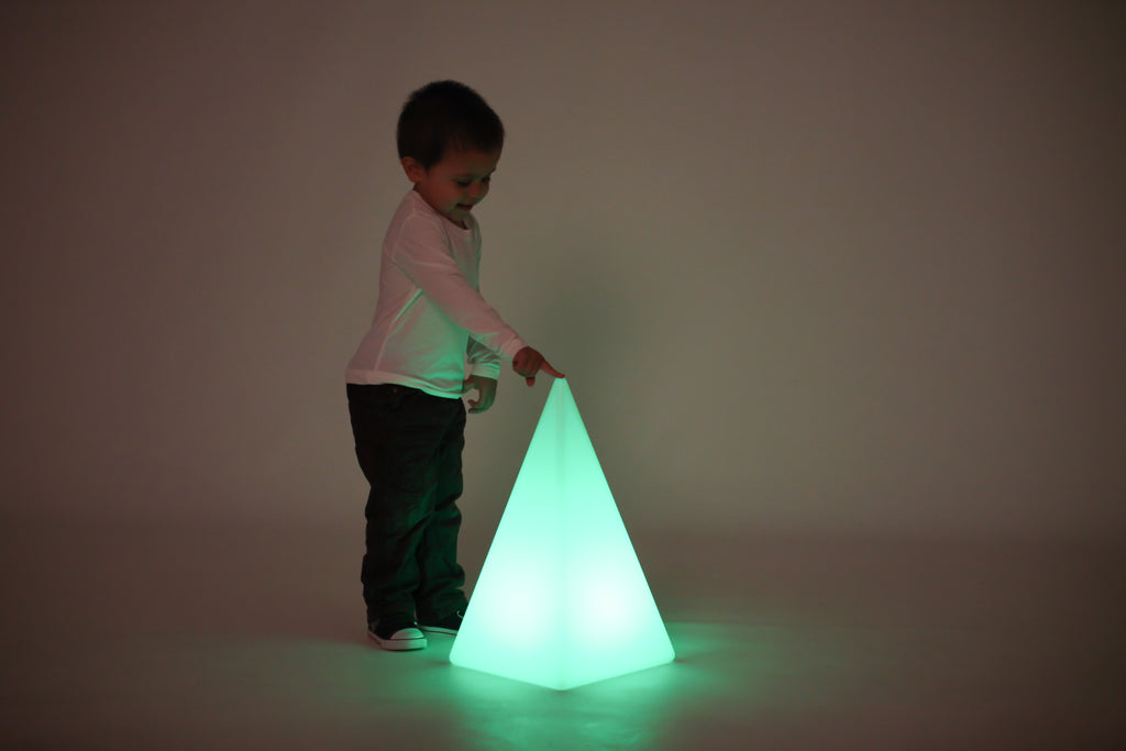 Child standing with glowing light pyramid, bright green light