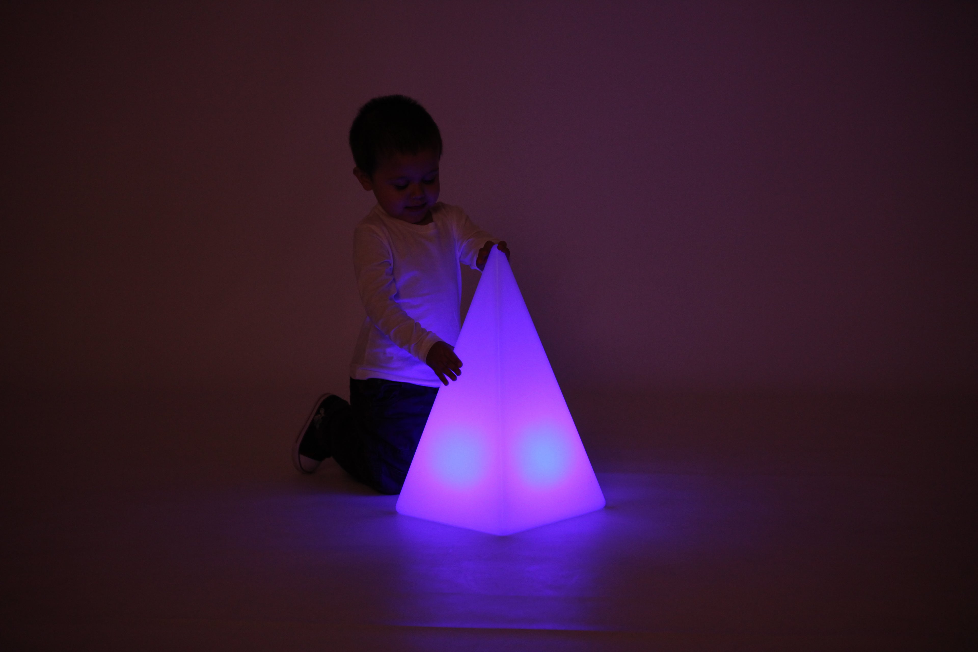 Child playing with glowing light pyramid, violet-purple light