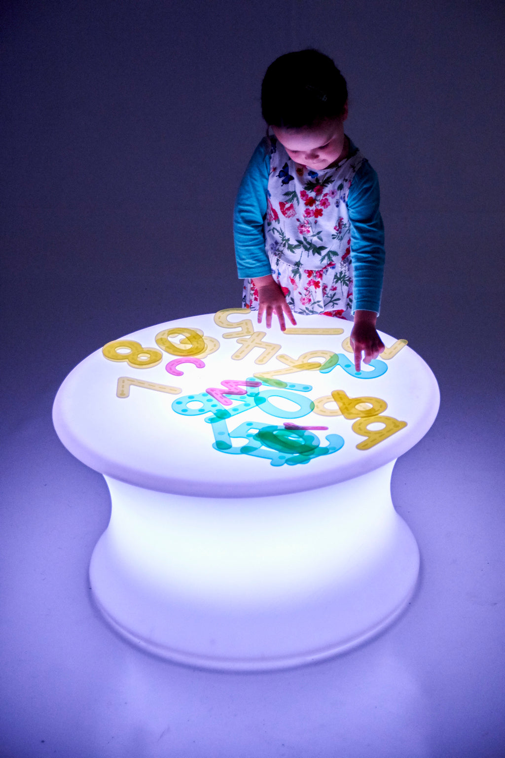 Sensory glow table with a round illuminated top displaying multicolor number icons