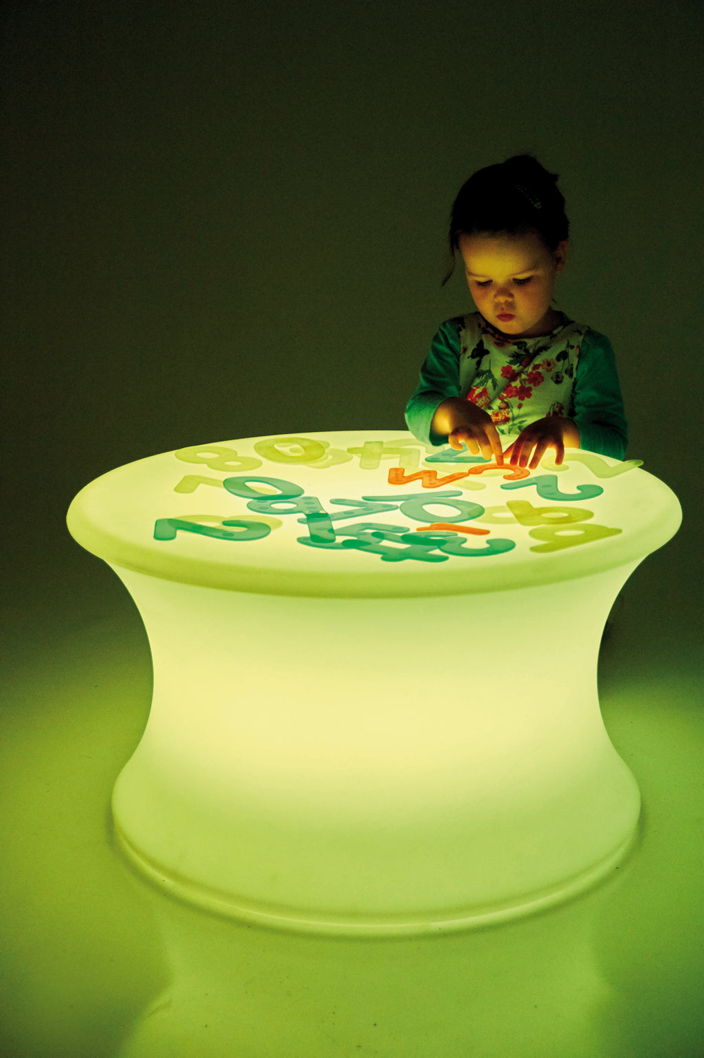 Sensory glow table with a green-glowing round top featuring multicolor number shapes