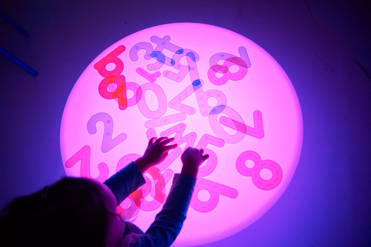 Sensory glow table with a round illuminated top and colorful number shapes, close-up view