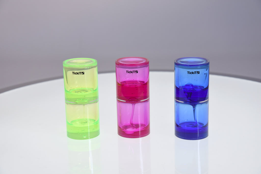 Three tickit ooze tubes: lime green, pink, and blue on reflective surface