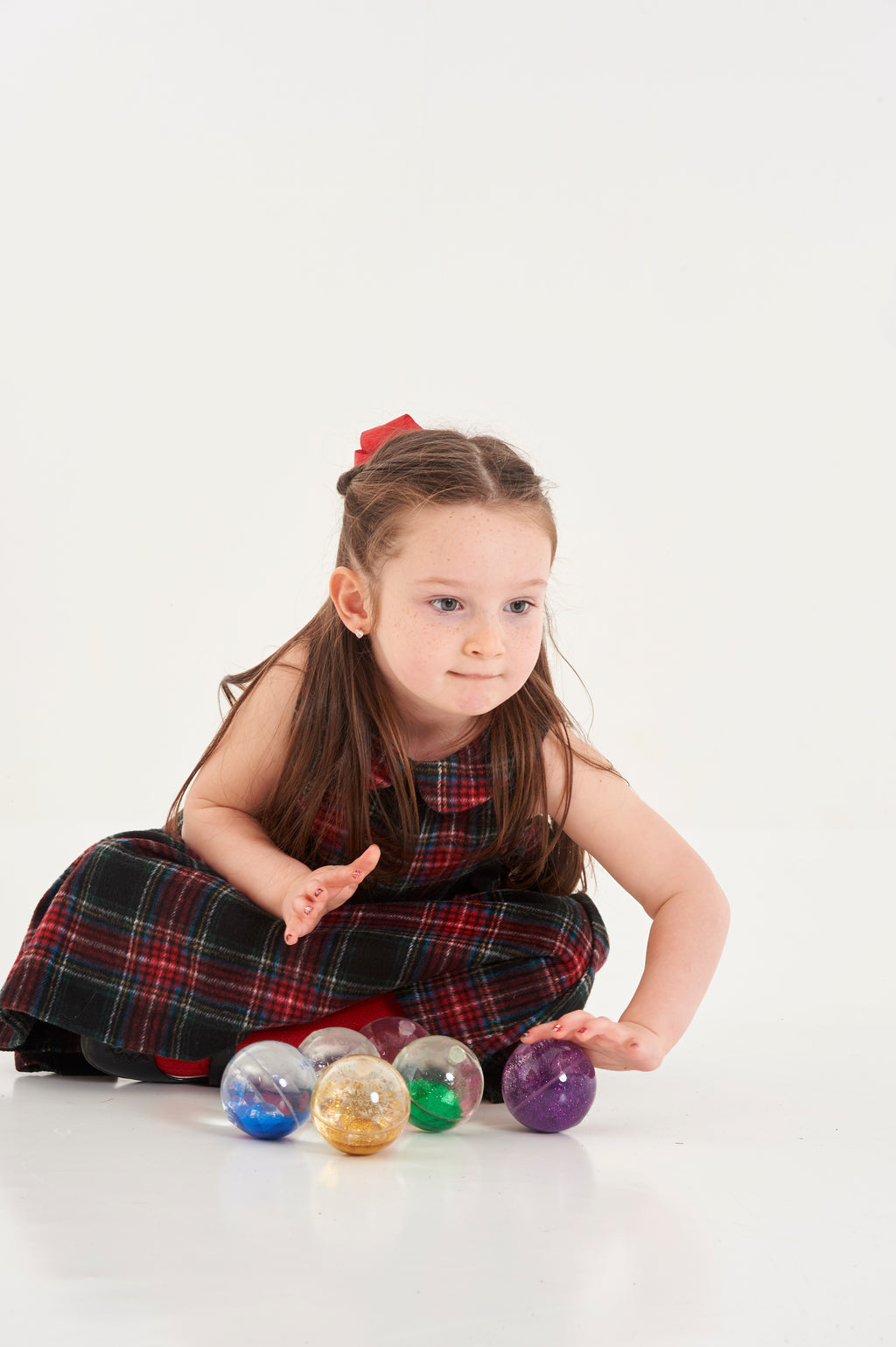 Rainbow glitter sensory balls with a child sitting among the balls