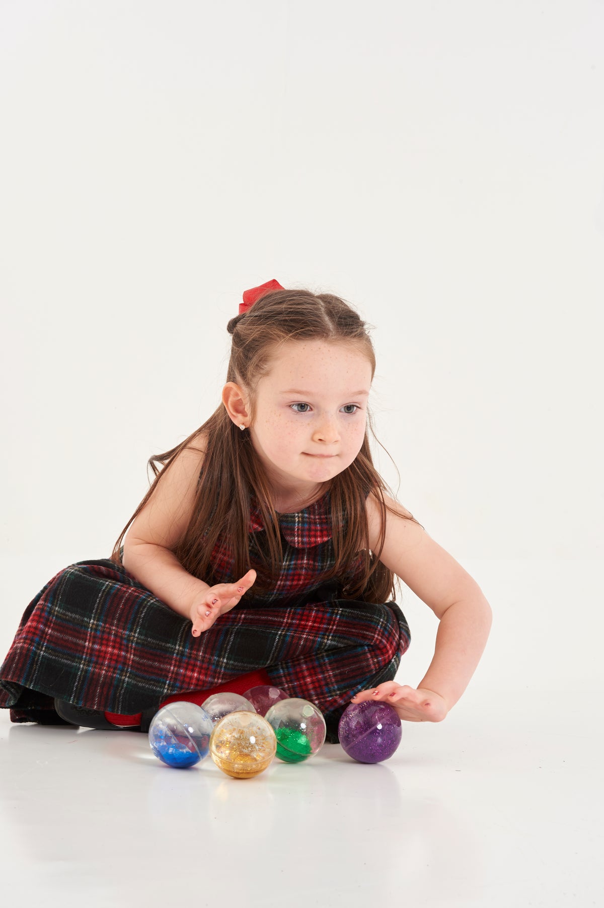 Rainbow glitter sensory balls with a child sitting among the balls
