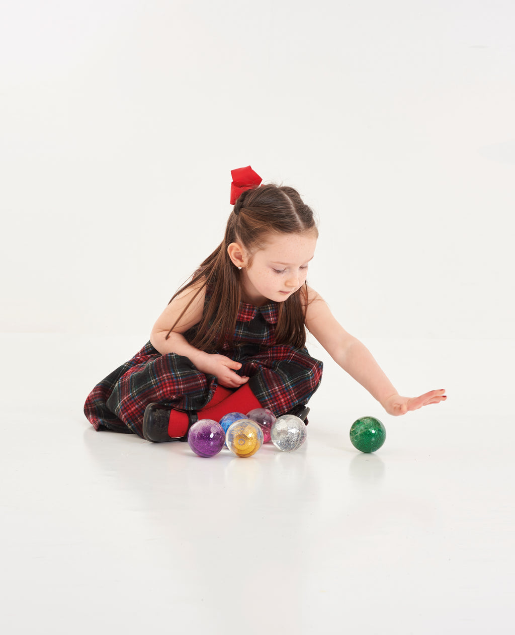 Scattered glitter sensory balls in mixed colors with a child playing