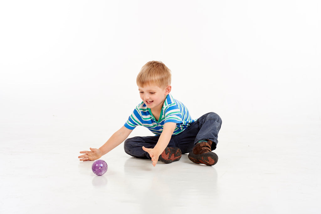 Set of glitter sensory balls with one purple ball on the floor