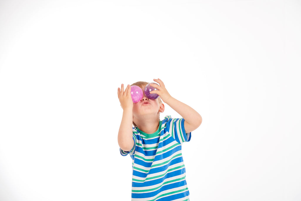 Purple glitter sensory ball held to the eyes by a child