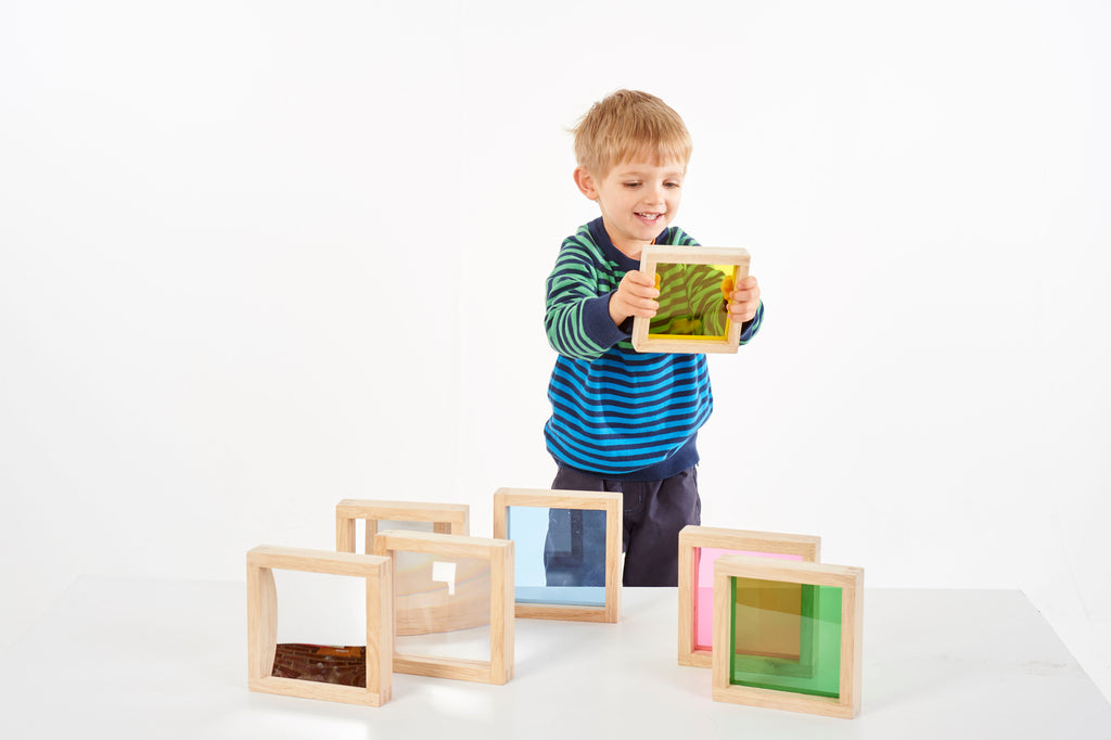 Child playing with wooden square sensory blocks featuring colored translucent panels