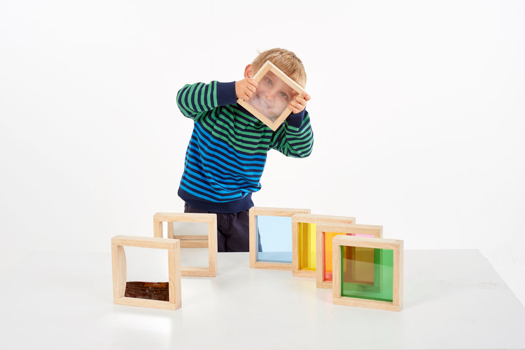 Child holding a wooden square sensory block while using more colored blocks