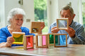Two seniors holding wooden square sensory blocks with colorful translucent insets