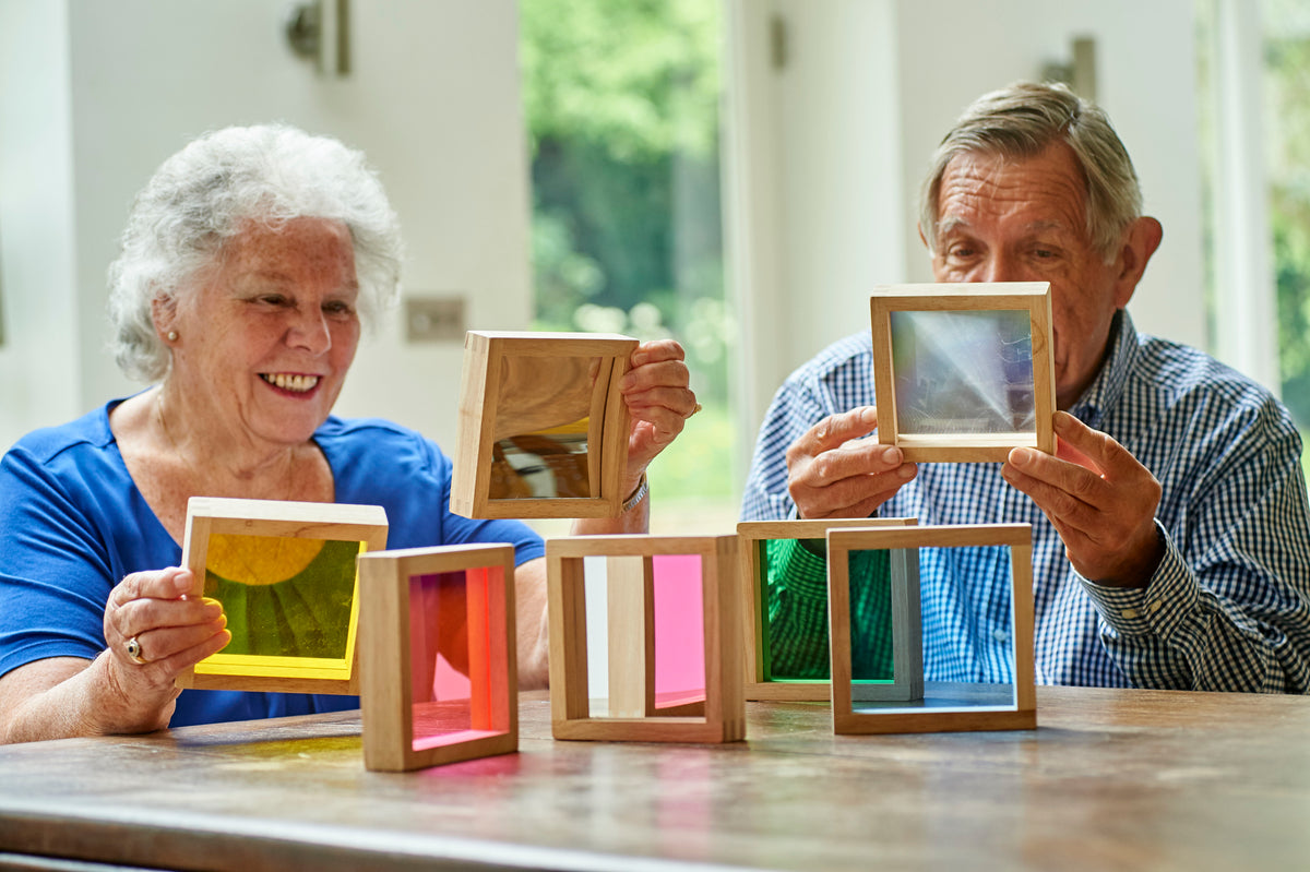 Two seniors holding wooden square sensory blocks with colorful translucent insets