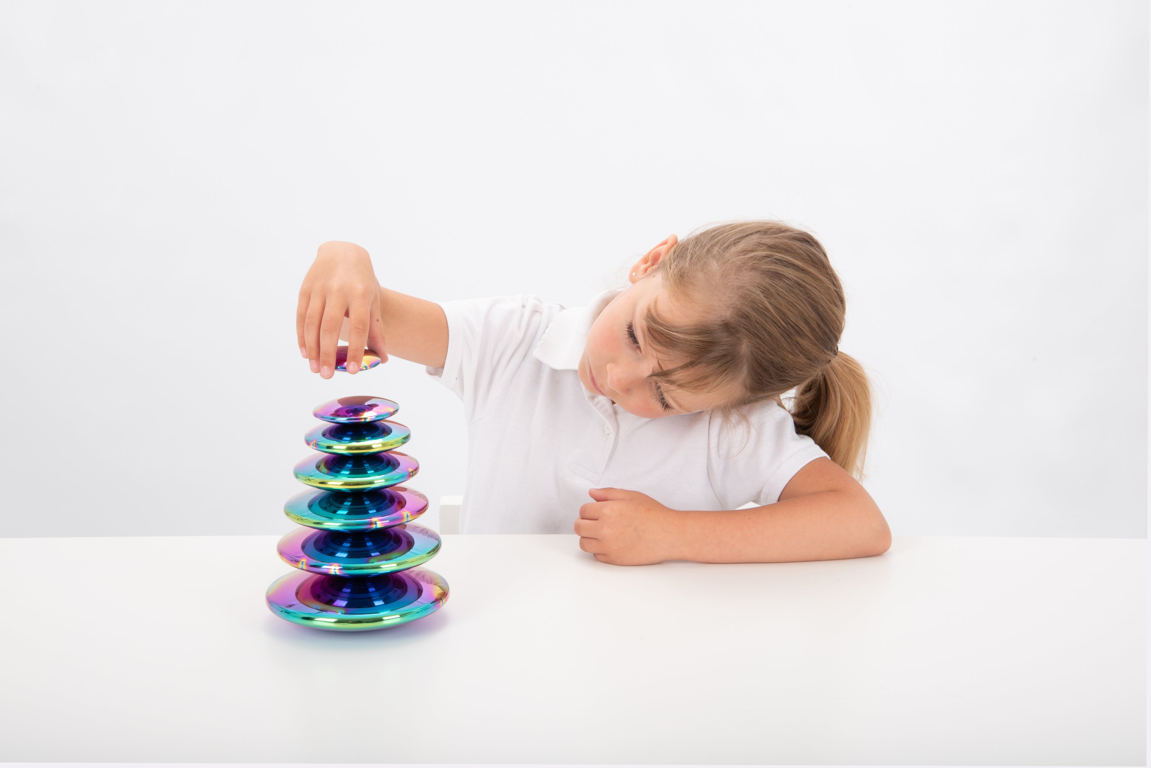 Iridescent steel buttons set of 7, stacked discs being pressed by child