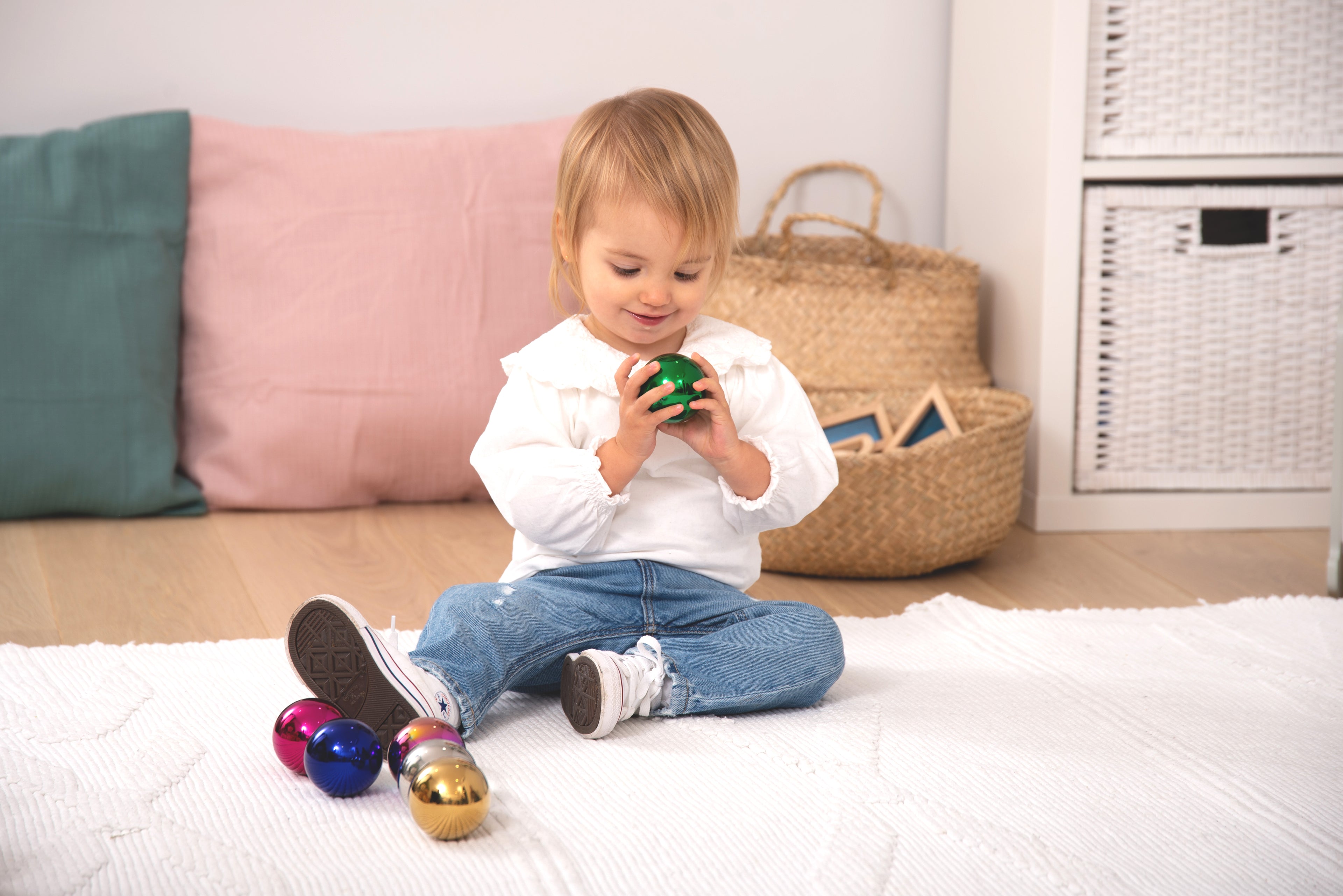 Steel sensory balls set of six, shiny blue, green, pink and gold balls in child hands
