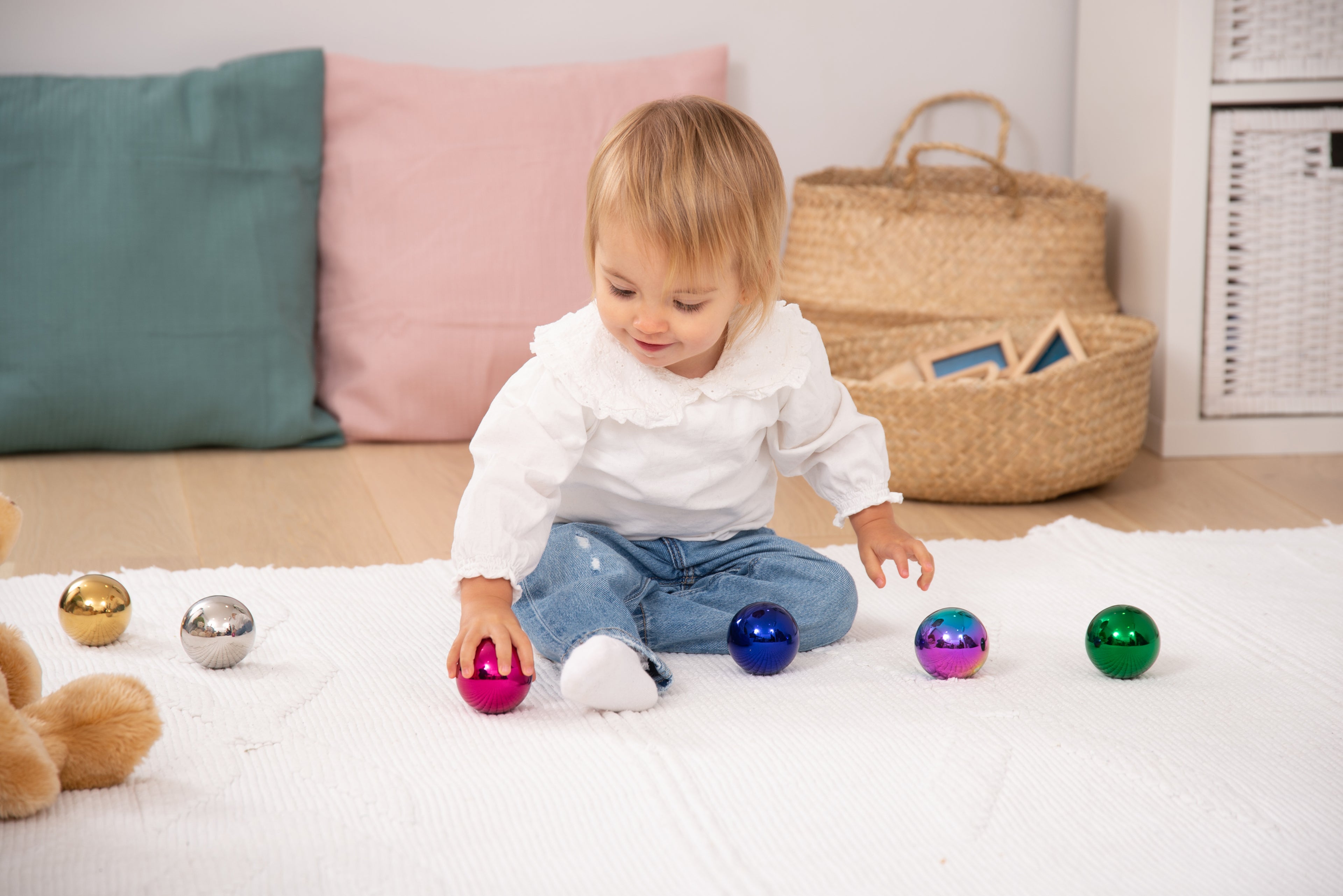 Steel sensory balls set of six, glossy blue, pink, green and gold balls on floor