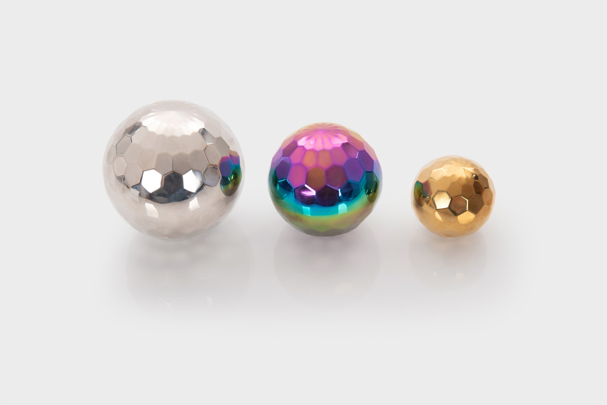 Three iridescent metallic mosaic balls: silver, rainbow-purple, and gold