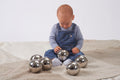 Set of six shiny steel sensory balls, baby handling a ball among the set.